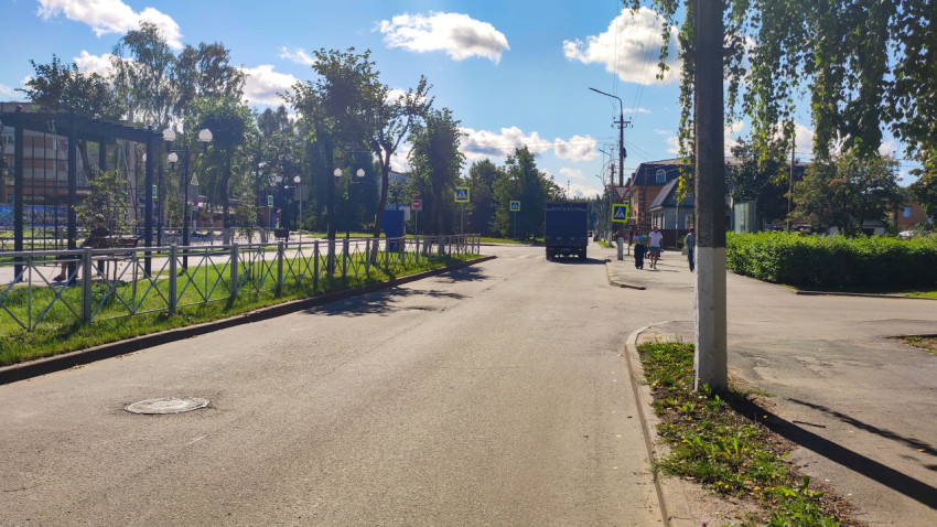 Почтовый грузовик на улице у пешеходного перехода и остановочного павильона в жилом районе