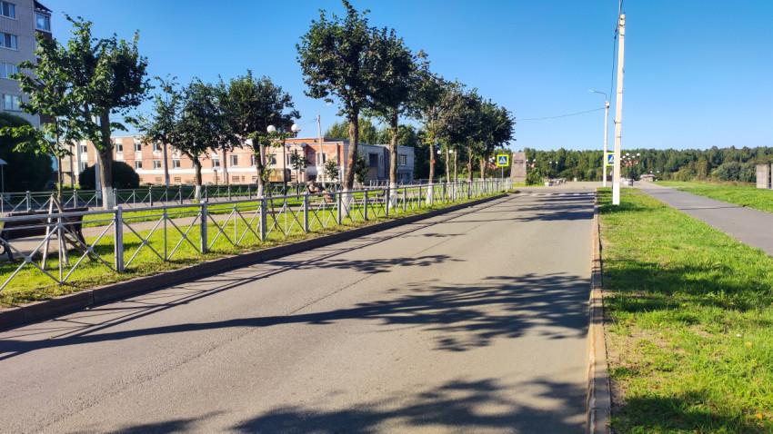 Пустая дорога с ограждением и лавочками тянется к знаку пешеходного перехода