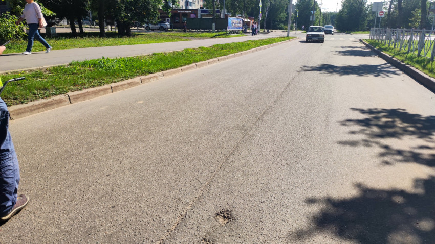 Пустой участок дороги с ограждением, дорожными знаками и деревьями вдоль обочины