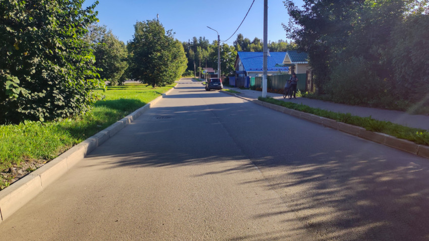 Прямая улица с пешеходным переходом и человеком с велосипедом у обочины