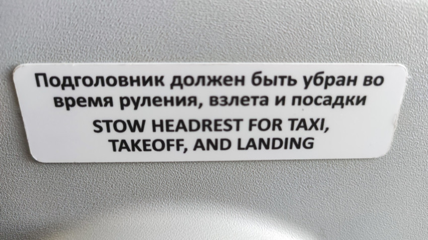 Билингвальная инструкция о подголовнике на кресле самолёта