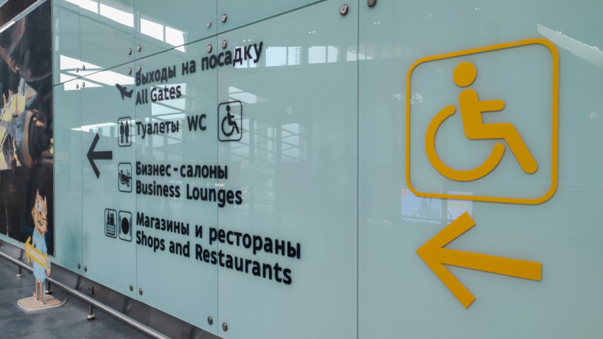 Жёлтый знак доступности и стрелка на стеклянной перегородке терминала