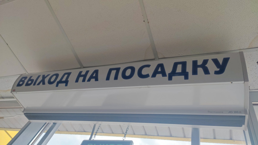 Указатель «Выход на посадку» под потолком в зоне аэропортового прохода