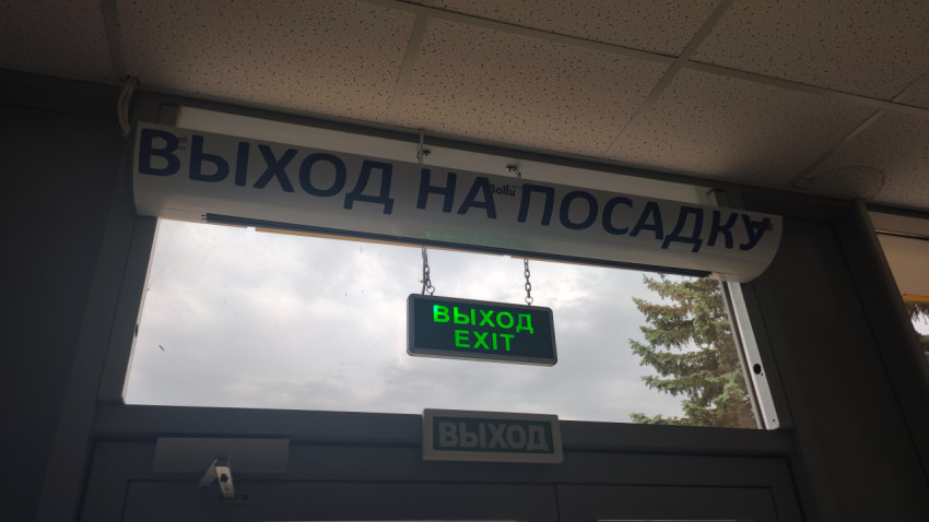 Входной проём с вывеской «Выход на посадку» и зелёным световым указателем «ВЫХОД EXIT»