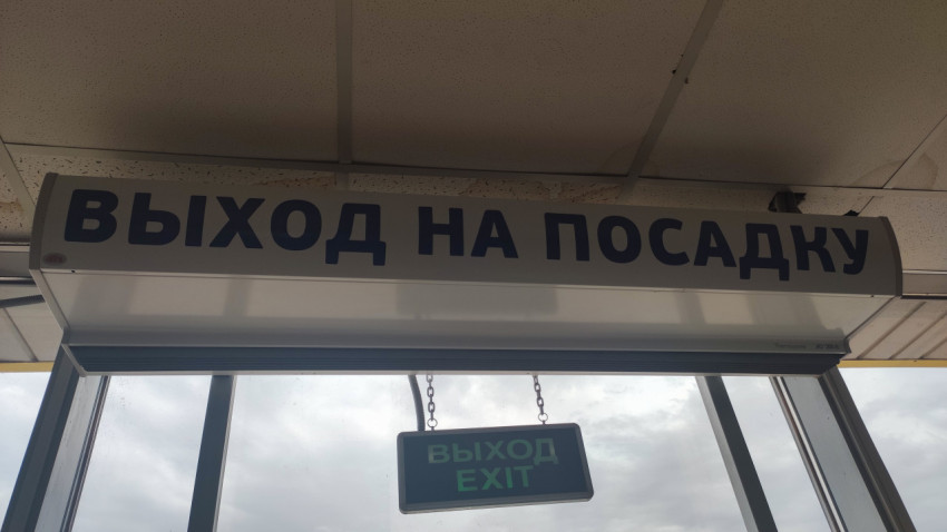 Табличка «Выход на посадку» в аэропорту над входом с подвесным указателем EXIT