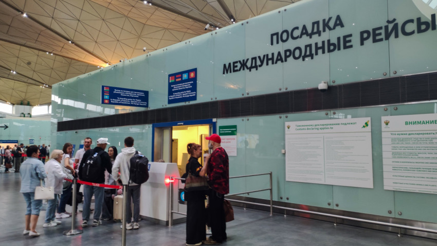 Вход в международную зону: люди у ленты и стенды таможни на стеклянной стене