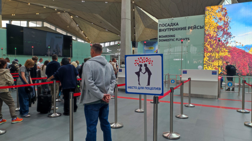 Люди в очереди у зоны посадки на внутренние рейсы в аэропорту