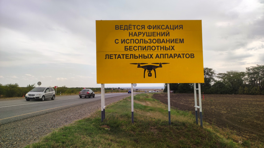 Жёлтый придорожный щит о фиксации нарушений с беспилотников на трассе