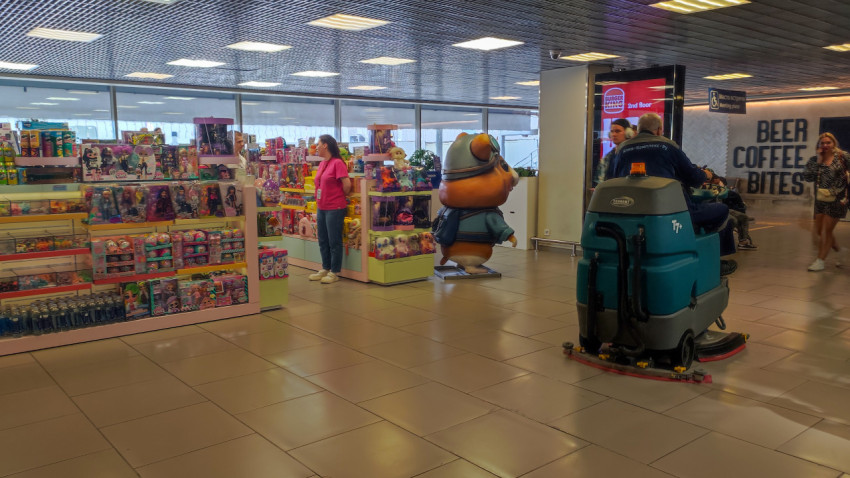 Зал аэропорта с магазином игрушек и уборочной машиной