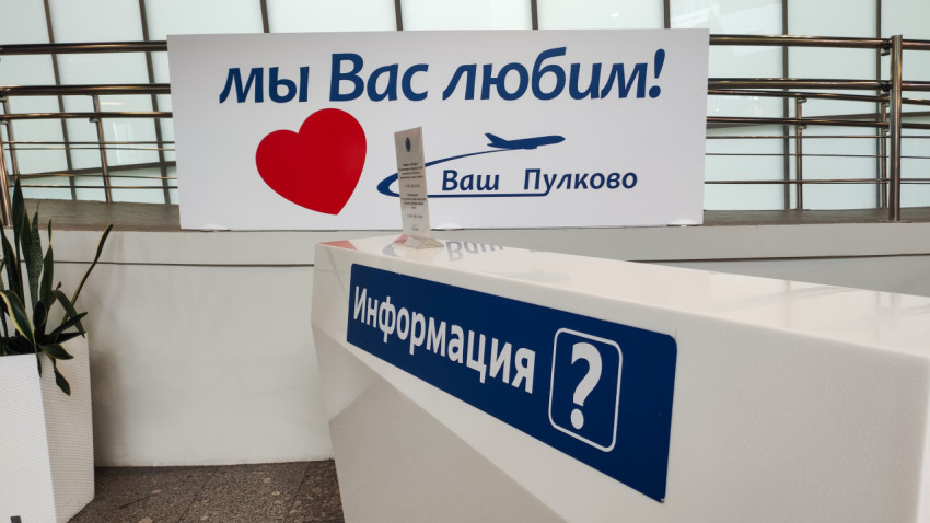 Стойка «Информация» с плакатом «Мы вас любим!» на фоне перил и панелей