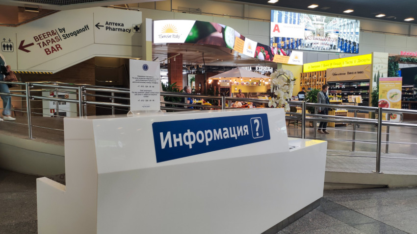 Стойка «Информация» у перил на фоне фудкорта и вывесок терминала