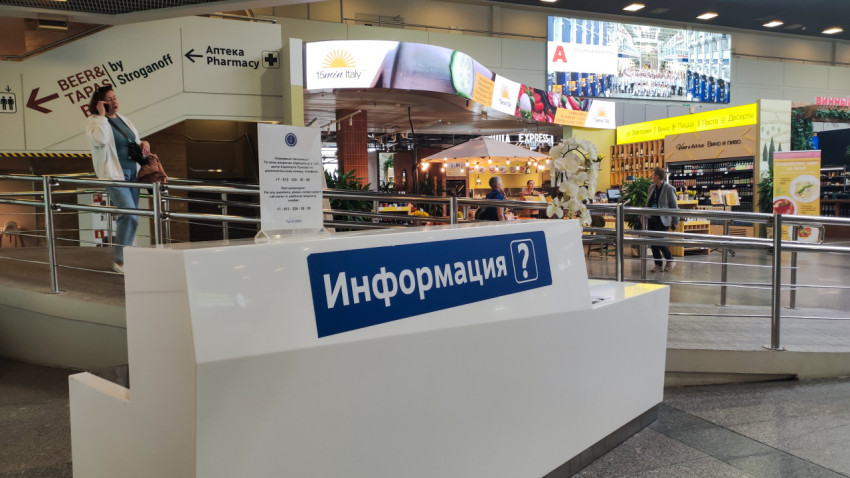 Стойка «Информация» в терминале на фоне фудкорта и проходящих людей