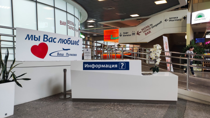 Информационная стойка аэропорта с табличкой «Мы вас любим!»
