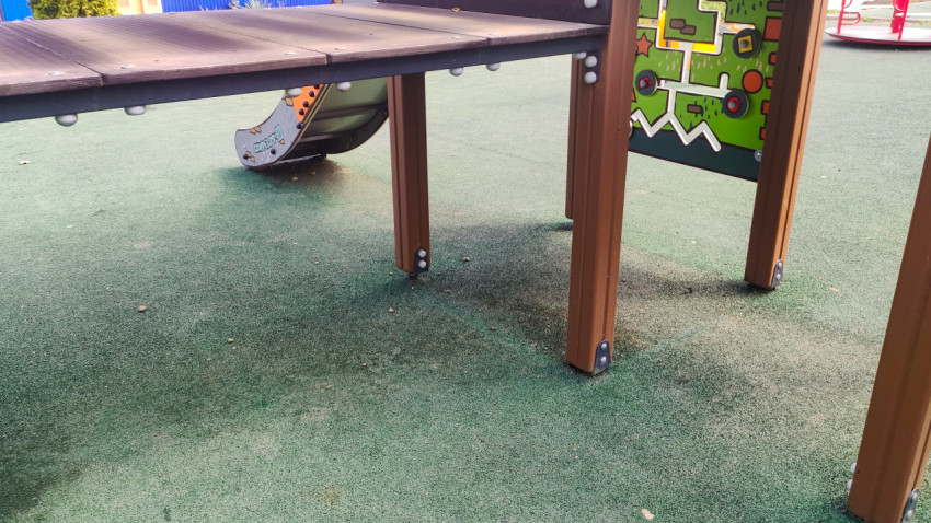 Деревянные опоры игрового комплекса на зелёном резиновом покрытии