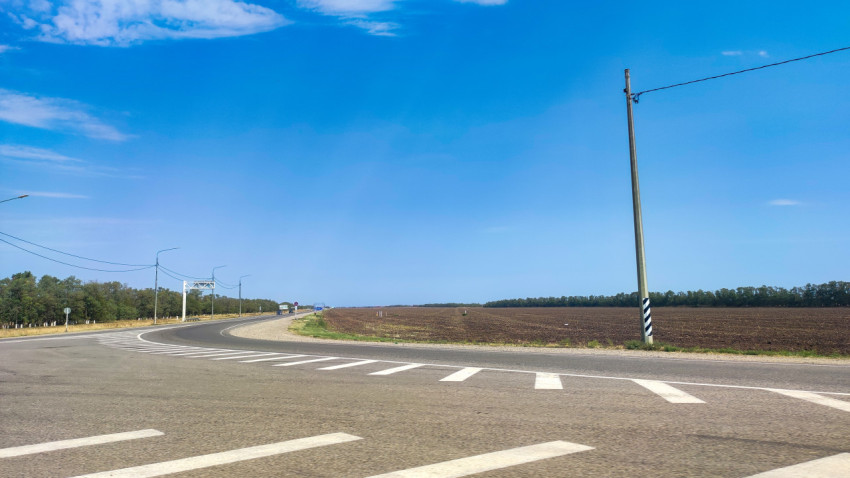 Поворот на сельской развязке, дорожная разметка и поля по сторонам шоссе