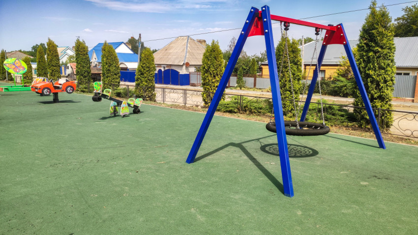 Качели-гнездо на металлической раме на детской площадке