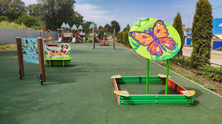 Детская площадка с песочницей и панно-бабочкой на зелёном покрытии