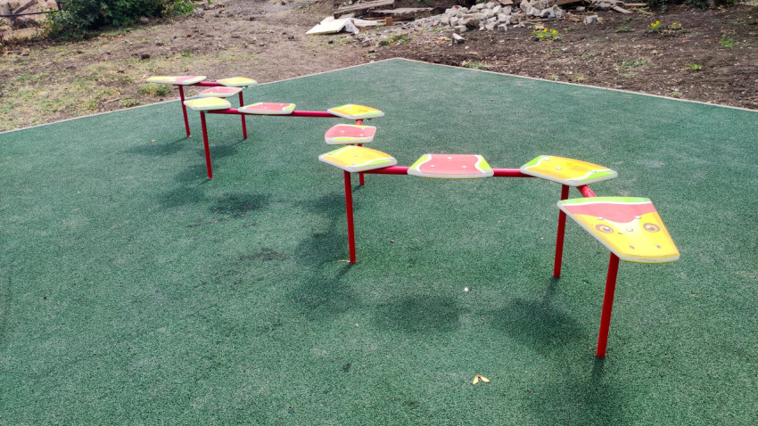 Баланс-дорожка из платформ на стойках на детской площадке с зелёным покрытием