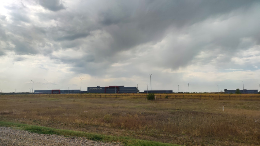 Складской комплекс STAVROPOL AUTO за забором на фоне степного поля и грозовых облаков