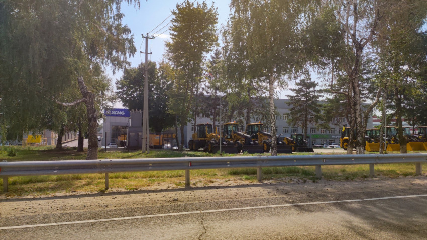 Длинная линейка тракторов на площадке у трассы с флагами