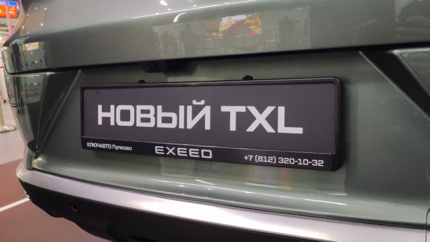 Табличка «Новый TXL» и камера заднего вида на крышке багажника