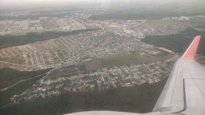 Крыло самолёта над пригородной застройкой и дорожной сетью