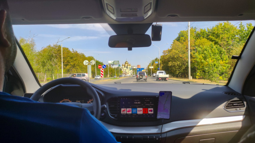 Вид из салона автомобиля на городскую дорогу и храм с куполами