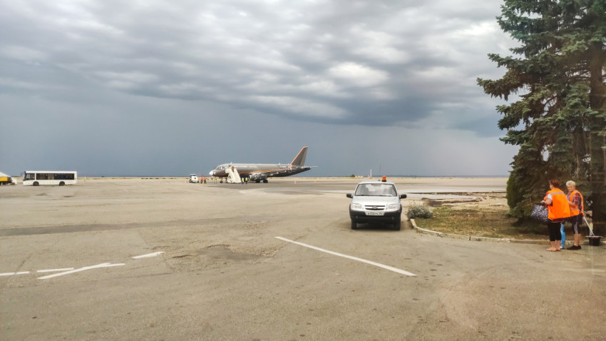 Перрон с самолётом у трапа, служебной машиной и работниками у края площадки