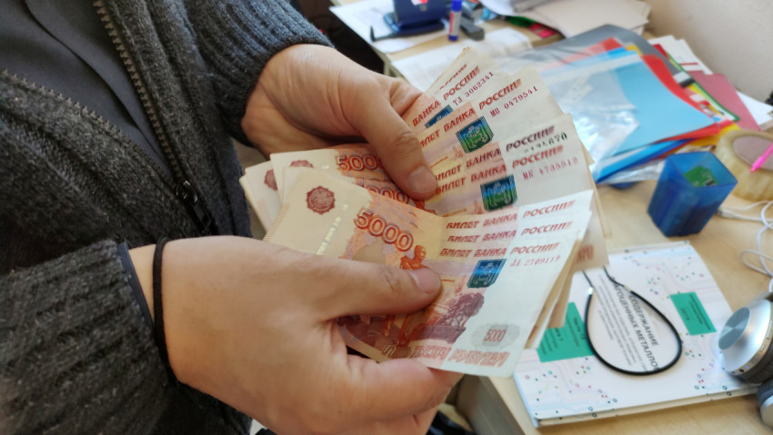 Человек держит пачку денег в руках