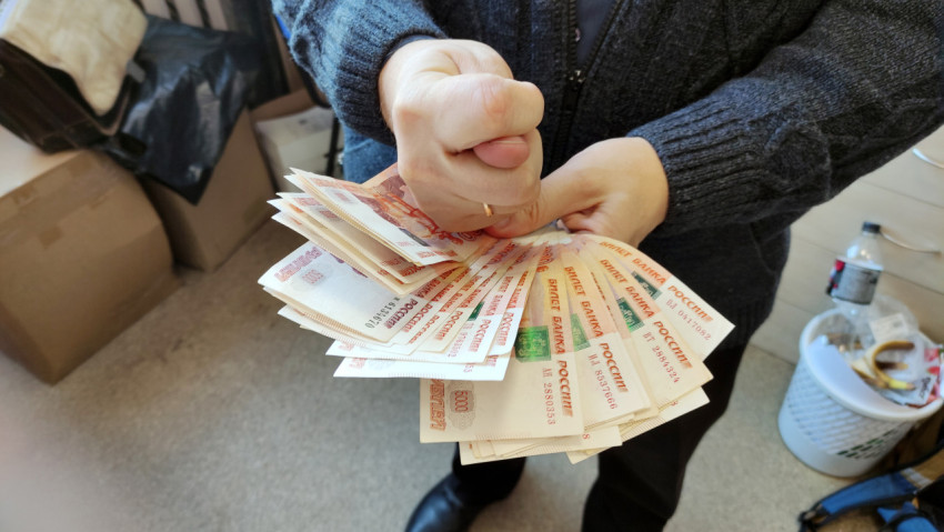 Человек держит в руках большую кучу денег