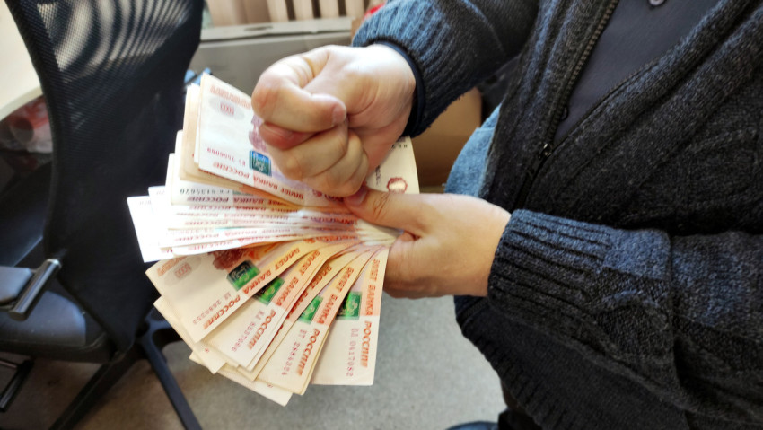 Человек держит в руке пачку денег
