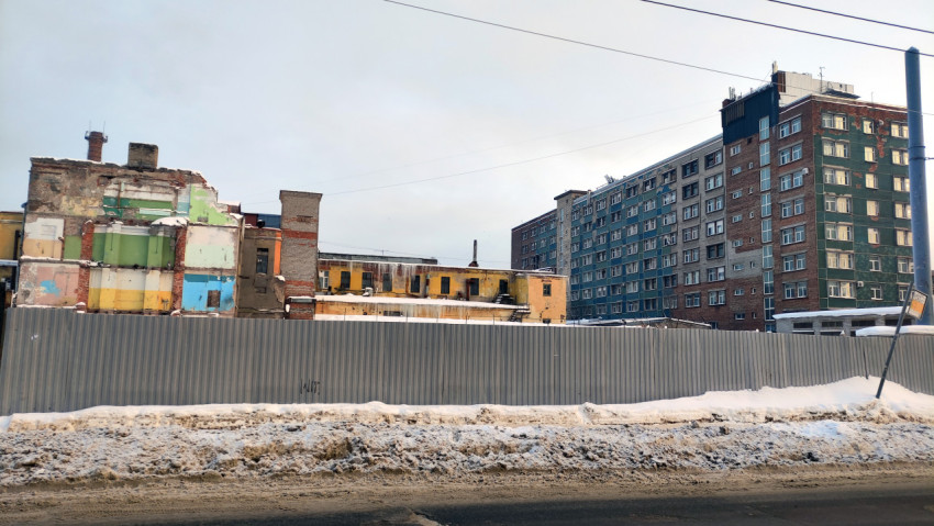 Городская заснеженная улица и зданния завода на заднем плане