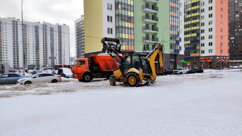 Трактор грузит снег в грузовик