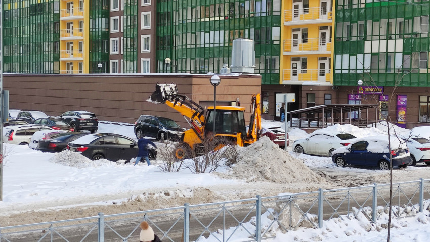 Трактор чистит снег на парковке