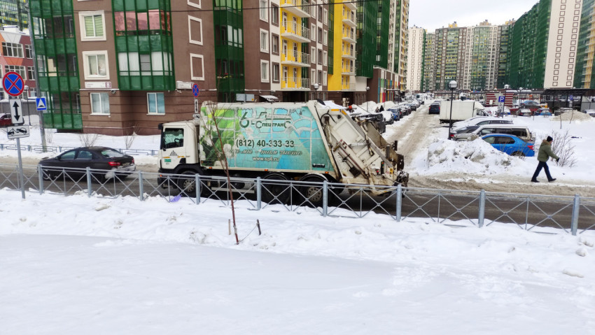 Мусоровоз движется по снежной улице