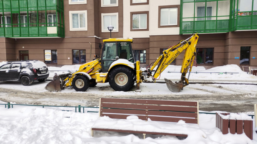 Бульдозер припаркован в снегу перед домом