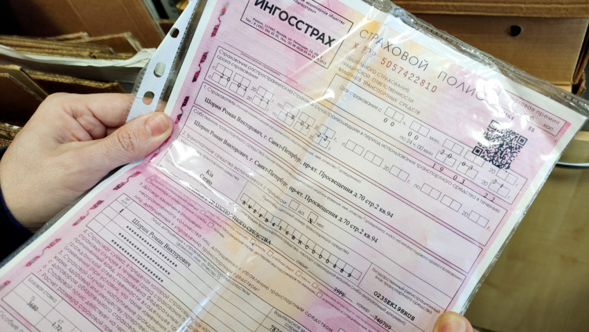 Человек держит в руках страховой полис