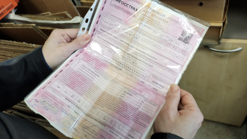 Человек держит автостраховой полис в руках