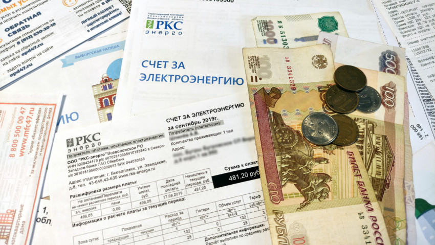Деньги на вершине стопки счетов за электричество