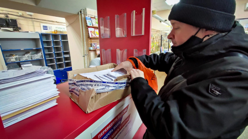 Клиент занимается сортировкой корреспонденции в помещении почтового отделения
