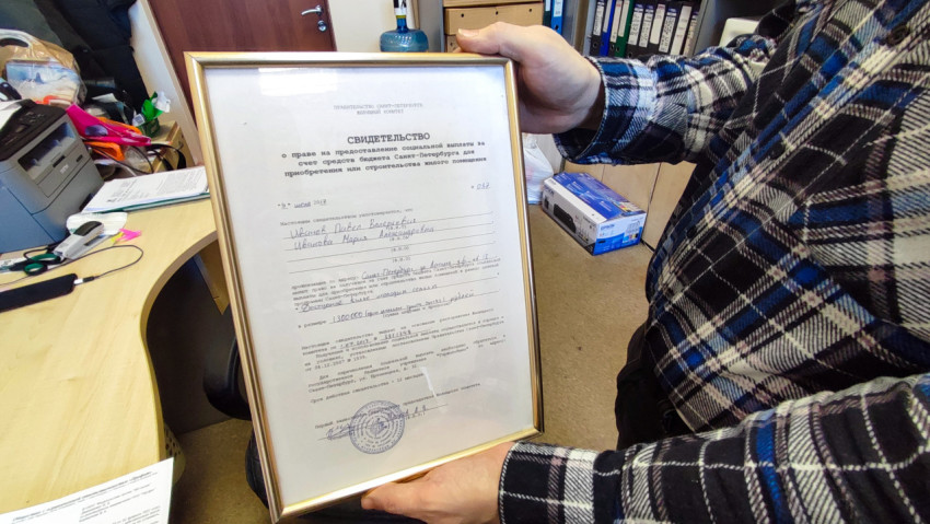 мужчина держит в руках сертификат на покупку квартиры от государства
