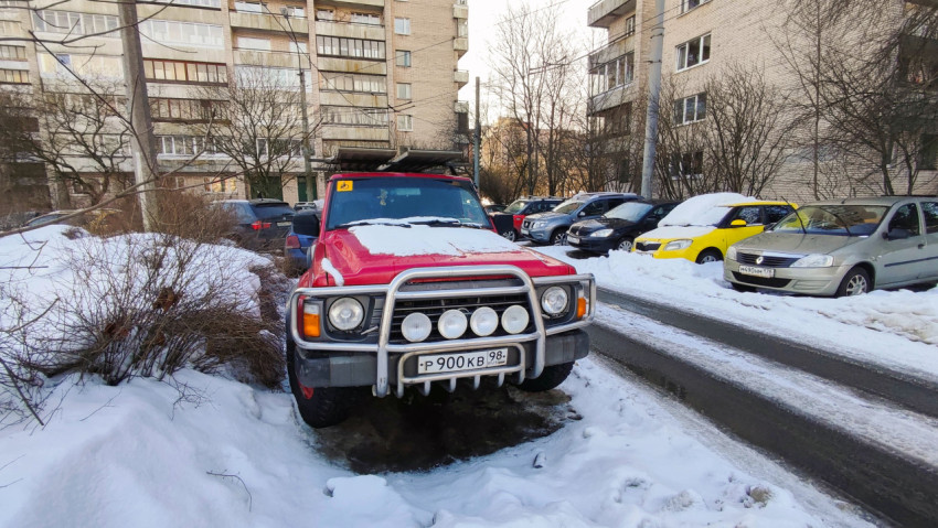 Красный Nissan Patrol припаркован во дворе