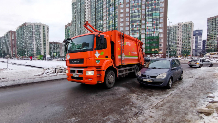 Мусоровоз проезжает мимо припаркованного автомобиля на городской улице