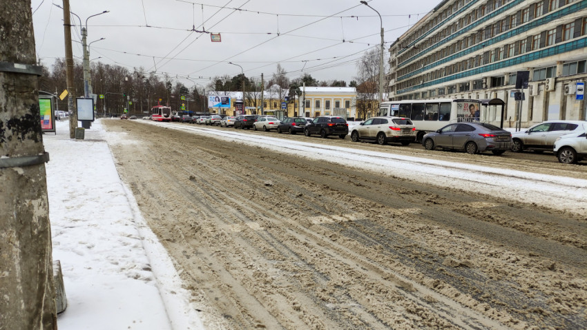 Загрязненный снег на дороге зимой в городе с машинами