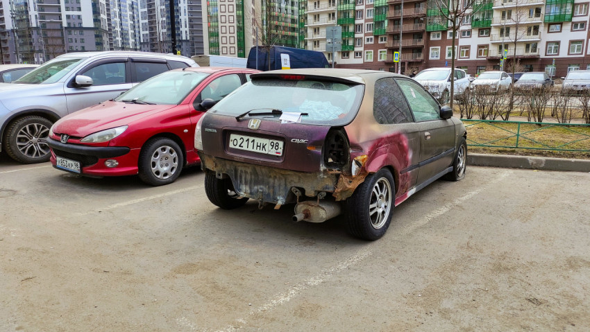 Поврежденный автомобиль на парковке рядом с жилыми домами