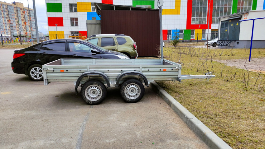 Прицеп для машины на парковке рядом с жилым комплексом