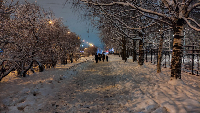Заснеженная городская аллея с вечерним освещением