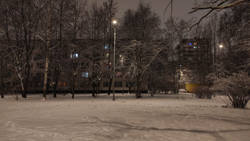 Заснеженный городской двор с освещенными фонарями ночью