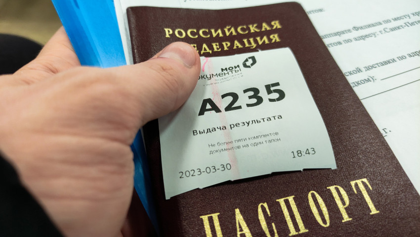Рука держит паспорт РФ с талоном на приём в МФЦ
