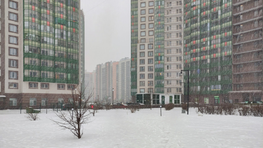 Зимний снегопад во дворе современных жилых высоток